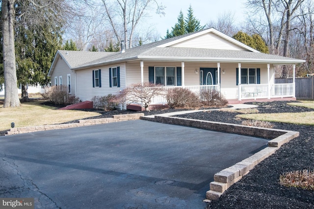 ranch-style house featuring covered porch and a front lawn