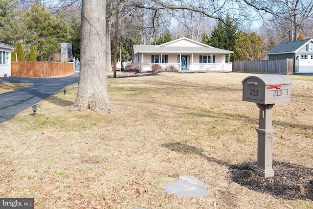 ranch-style home featuring covered porch and a front lawn