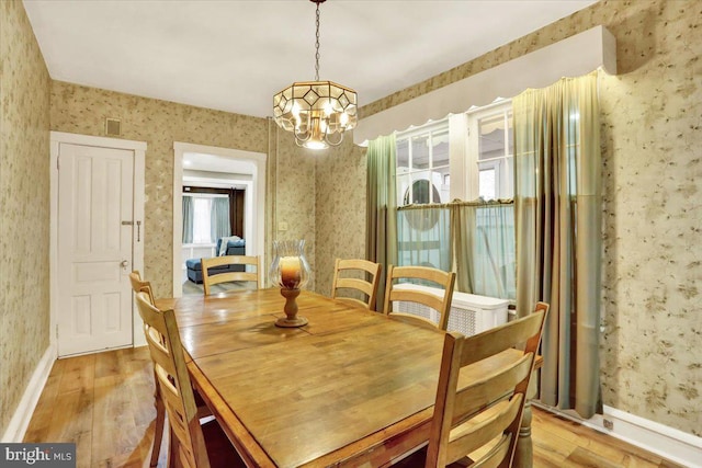 dining room featuring baseboards, light wood finished floors, and wallpapered walls