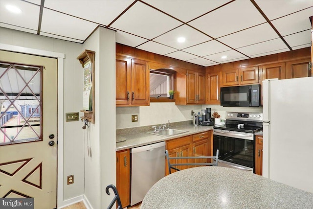 kitchen featuring stainless steel appliances, recessed lighting, light countertops, brown cabinetry, and a sink