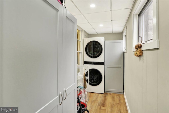 washroom with laundry area, light wood-type flooring, and stacked washer / drying machine