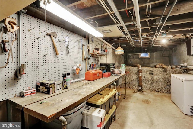 unfinished basement featuring a workshop area and refrigerator