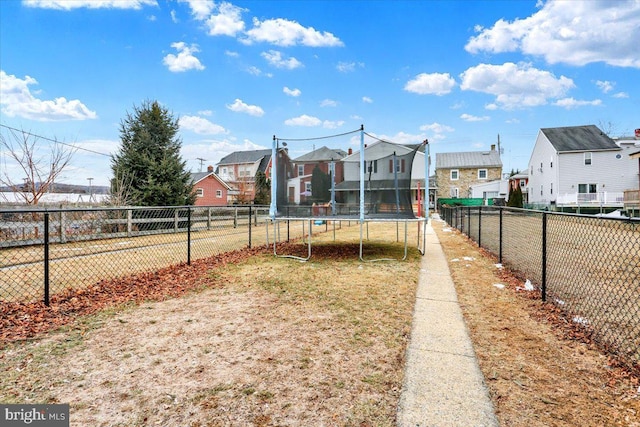 view of yard featuring a trampoline, a residential view, and fence