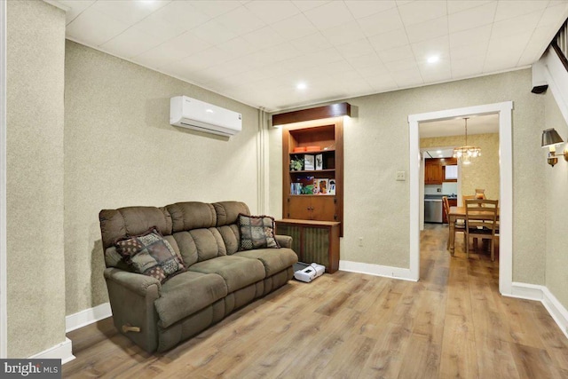 living room featuring light wood finished floors, baseboards, and an AC wall unit