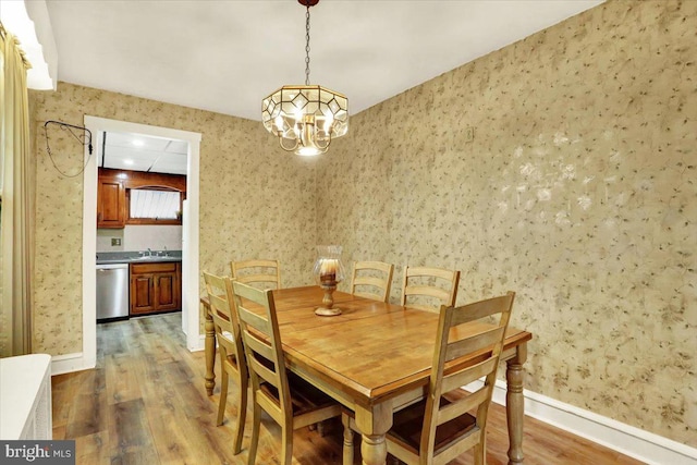 dining space featuring wallpapered walls, baseboards, dark wood finished floors, and a notable chandelier