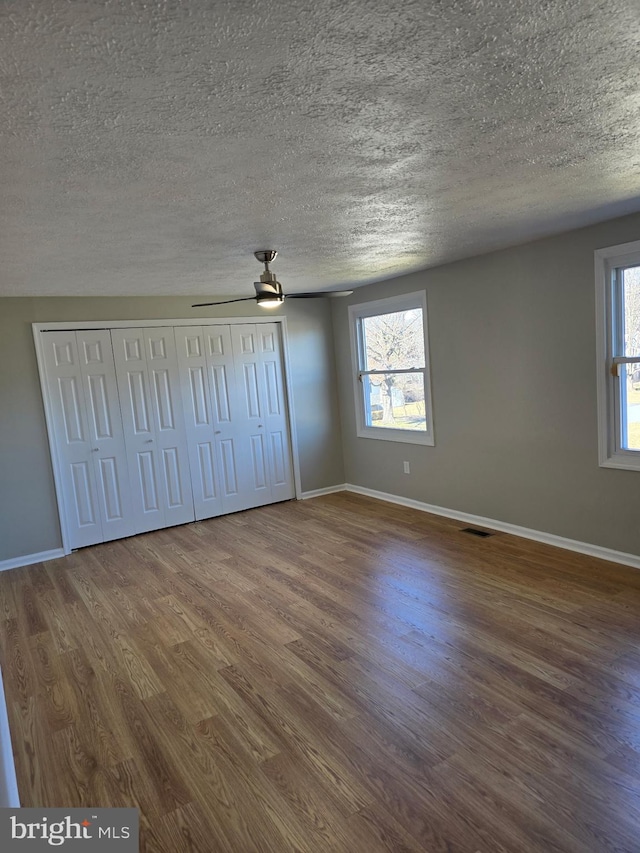 unfurnished bedroom with multiple windows, wood finished floors, and visible vents