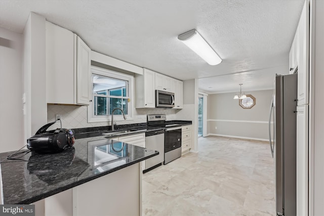 kitchen with a peninsula, a sink, stainless steel appliances, white cabinetry, and backsplash