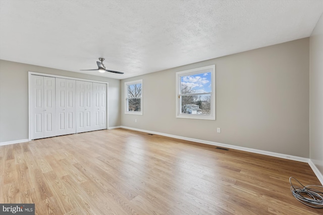 unfurnished bedroom featuring baseboards, a textured ceiling, and light wood-style floors