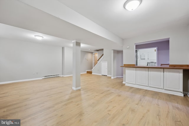 finished basement with light wood-type flooring, stairway, baseboards, and a baseboard radiator