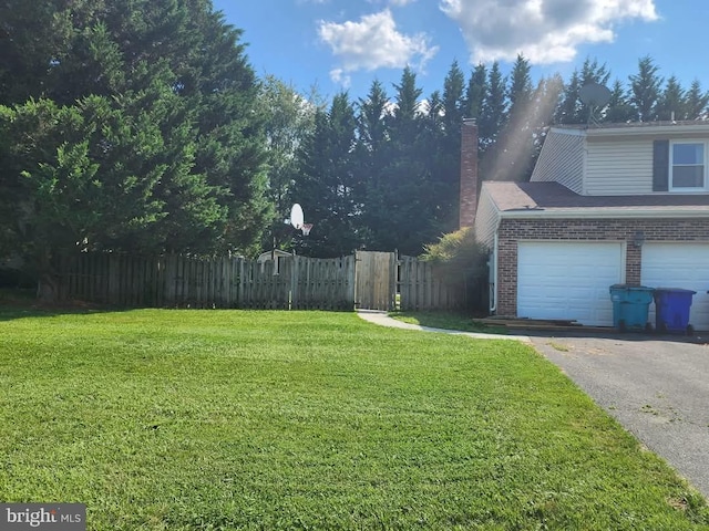 view of yard with aphalt driveway, fence, and a garage