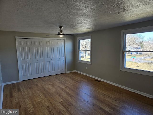 unfurnished bedroom with visible vents, a textured ceiling, baseboards, and wood finished floors