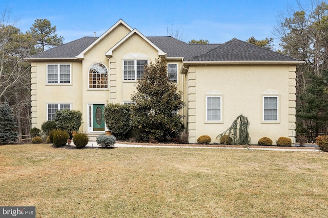 view of front of house featuring entry steps, roof with shingles, a front yard, and stucco siding