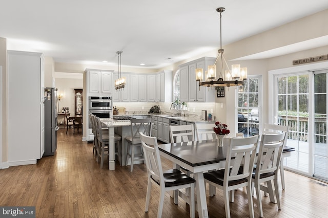 dining space with an inviting chandelier, visible vents, wood finished floors, and recessed lighting