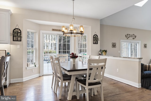 dining space featuring baseboards, a chandelier, and wood finished floors