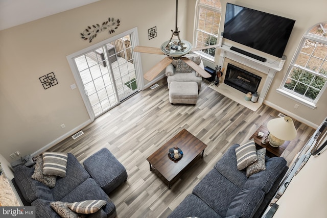 living room featuring a high end fireplace, visible vents, baseboards, and wood finished floors