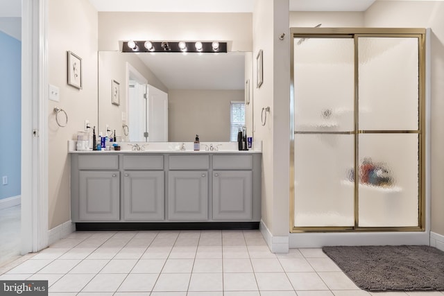 bathroom with double vanity, a shower stall, a sink, and tile patterned floors