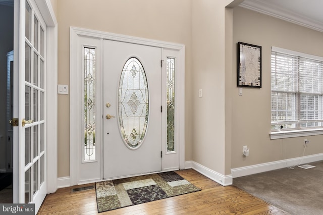 entryway with crown molding, hardwood / wood-style floors, visible vents, and baseboards