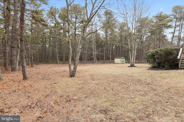 view of yard featuring a shed, fence, and an outbuilding