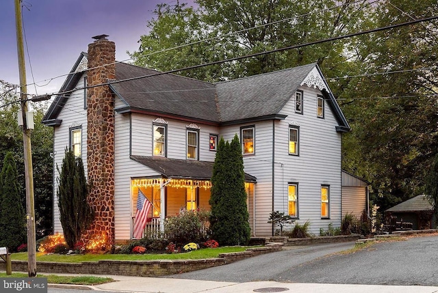 view of front of property featuring a shingled roof and a chimney