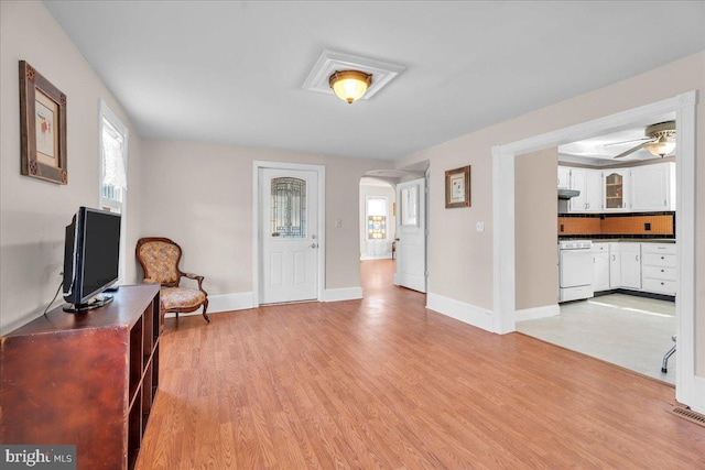 entrance foyer with arched walkways, light wood-style flooring, and baseboards