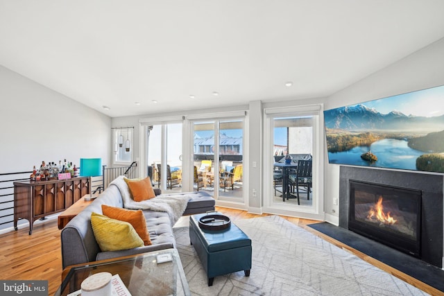 living room featuring light wood-style flooring and a fireplace with flush hearth