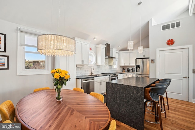 kitchen featuring white cabinets, visible vents, stainless steel appliances, and decorative light fixtures