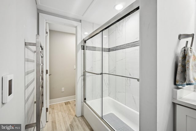 bathroom featuring shower / bath combination with glass door, baseboards, wood finished floors, and recessed lighting