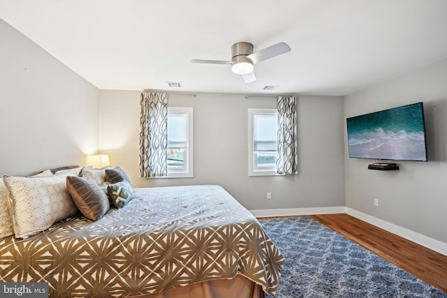 bedroom featuring visible vents, ceiling fan, baseboards, and wood finished floors