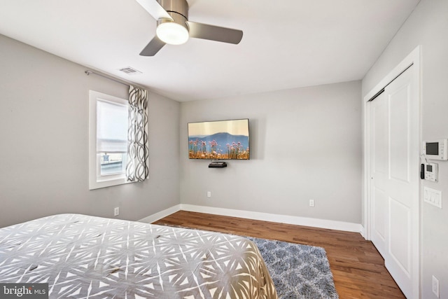 bedroom with a closet, ceiling fan, baseboards, and wood finished floors