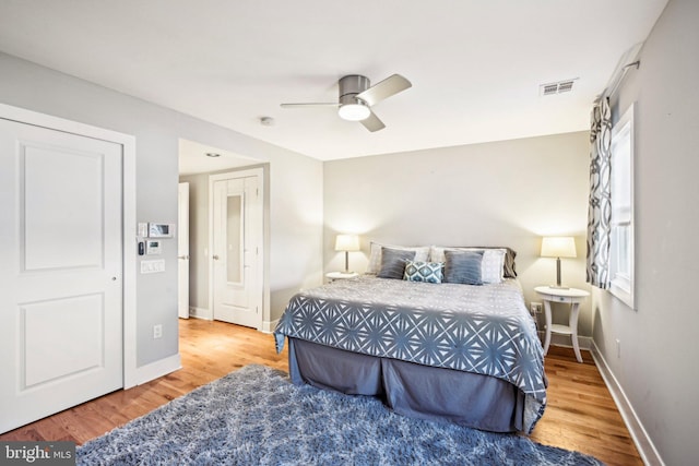 bedroom featuring visible vents, ceiling fan, baseboards, and wood finished floors