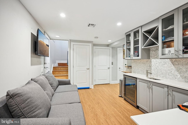 interior space with wine cooler, visible vents, light wood-style flooring, wet bar, and stairs