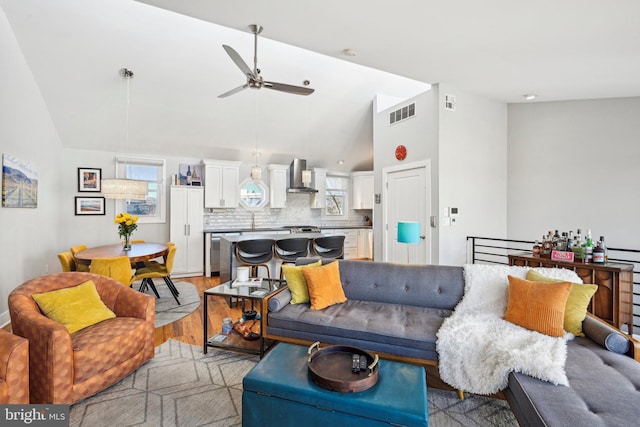 living room featuring visible vents, high vaulted ceiling, a ceiling fan, and light wood-style floors