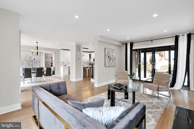 living room with light wood finished floors, visible vents, a notable chandelier, and recessed lighting