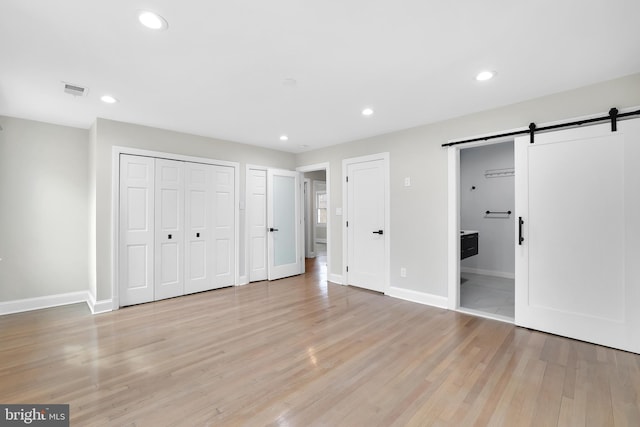 unfurnished bedroom featuring recessed lighting, baseboards, light wood finished floors, and a barn door