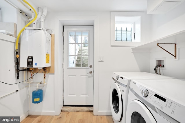 washroom with light wood-style floors, tankless water heater, washer and dryer, laundry area, and baseboards