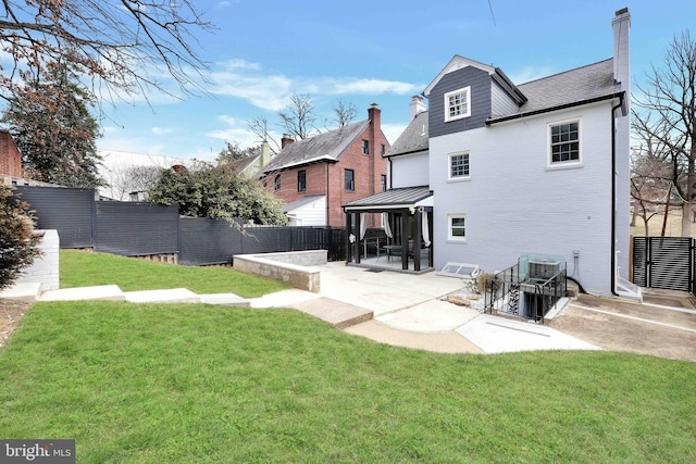 back of house with a patio, a yard, a chimney, and a fenced backyard