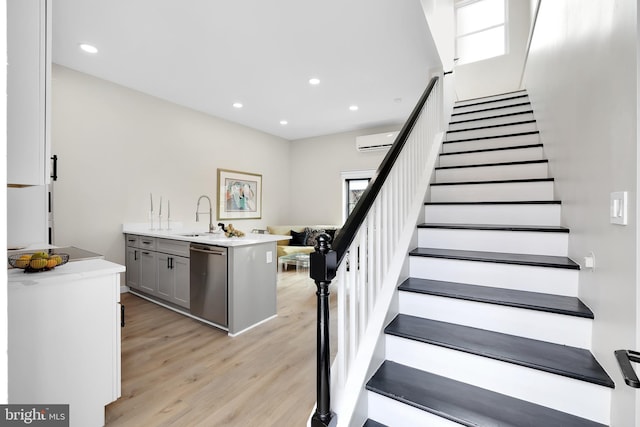 staircase with recessed lighting, an AC wall unit, and wood finished floors