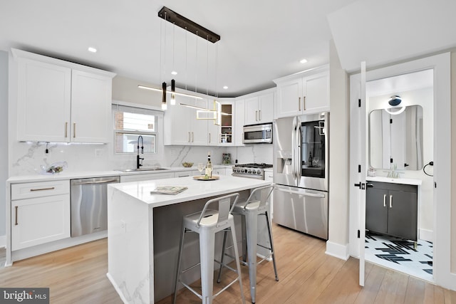 kitchen with stainless steel appliances, light countertops, glass insert cabinets, white cabinets, and a kitchen island