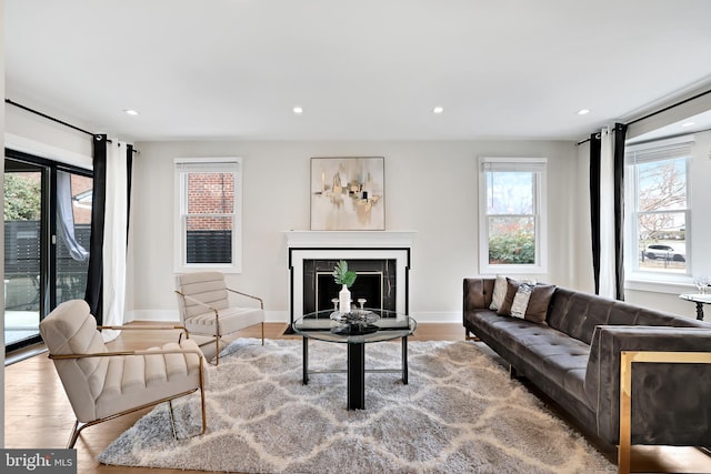 living area with light wood finished floors, a fireplace with flush hearth, and recessed lighting