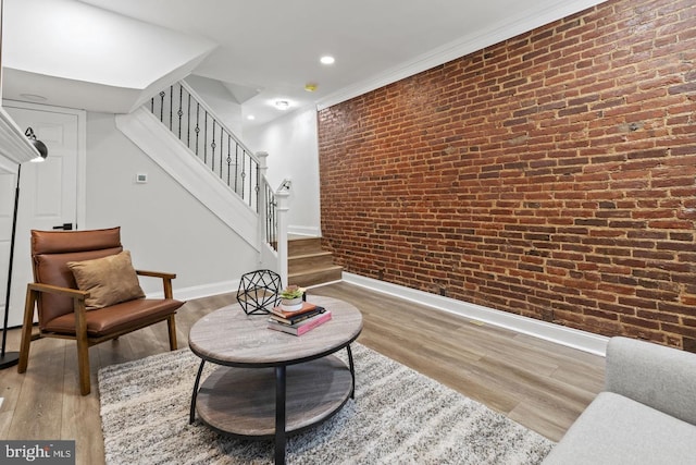 living area featuring stairs, wood finished floors, and brick wall