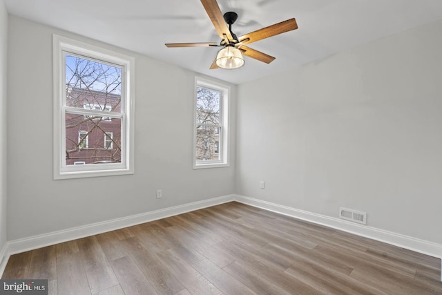 spare room with visible vents, a ceiling fan, baseboards, and wood finished floors