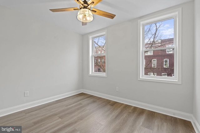 empty room with wood finished floors, baseboards, and a healthy amount of sunlight