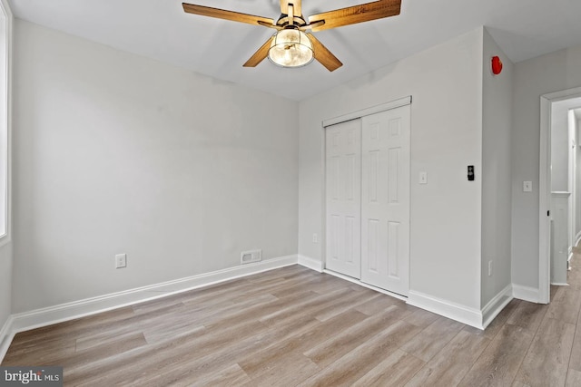 unfurnished bedroom featuring light wood finished floors, visible vents, a closet, and baseboards