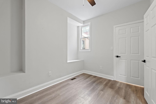 unfurnished bedroom featuring visible vents, a ceiling fan, baseboards, and wood finished floors