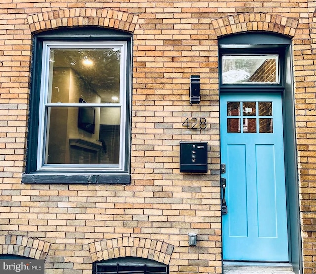 view of exterior entry featuring brick siding