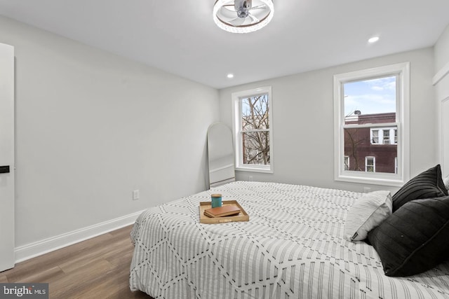 bedroom with recessed lighting, multiple windows, wood finished floors, and baseboards