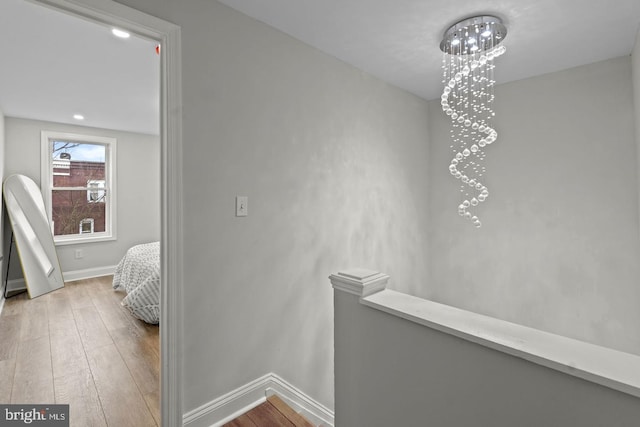 corridor with an upstairs landing, baseboards, and wood-type flooring