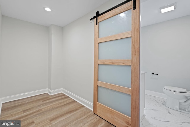 empty room with recessed lighting, marble finish floor, baseboards, and a barn door