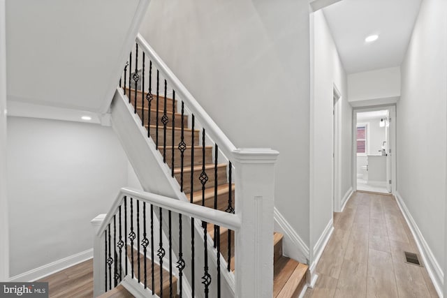 stairway with recessed lighting, visible vents, baseboards, and wood finished floors