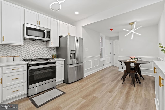 kitchen with decorative backsplash, appliances with stainless steel finishes, light wood-style flooring, and light countertops